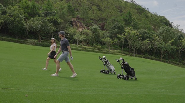 picture of the autonomous ROBERA AI Golf Caddy following behind golfers walking in fairway.